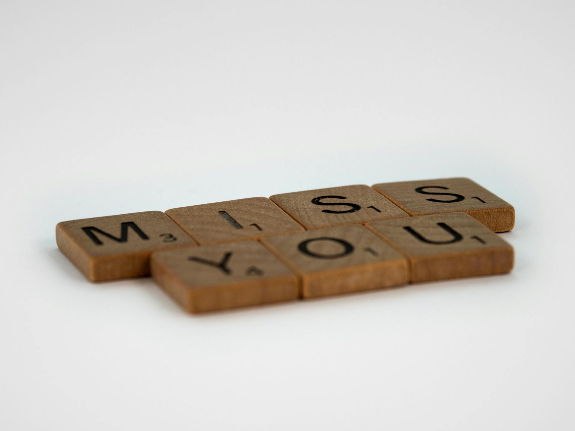 Scrabble tiles arranged to spell 'miss you' on a white background with space for text.