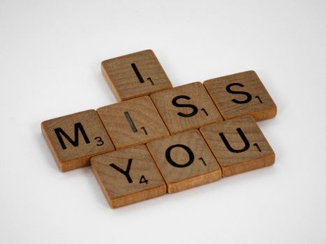 Close-up of Scrabble tiles arranged to spell 'I Miss You' on a white background. Perfect for conceptual messages and copy space needs.