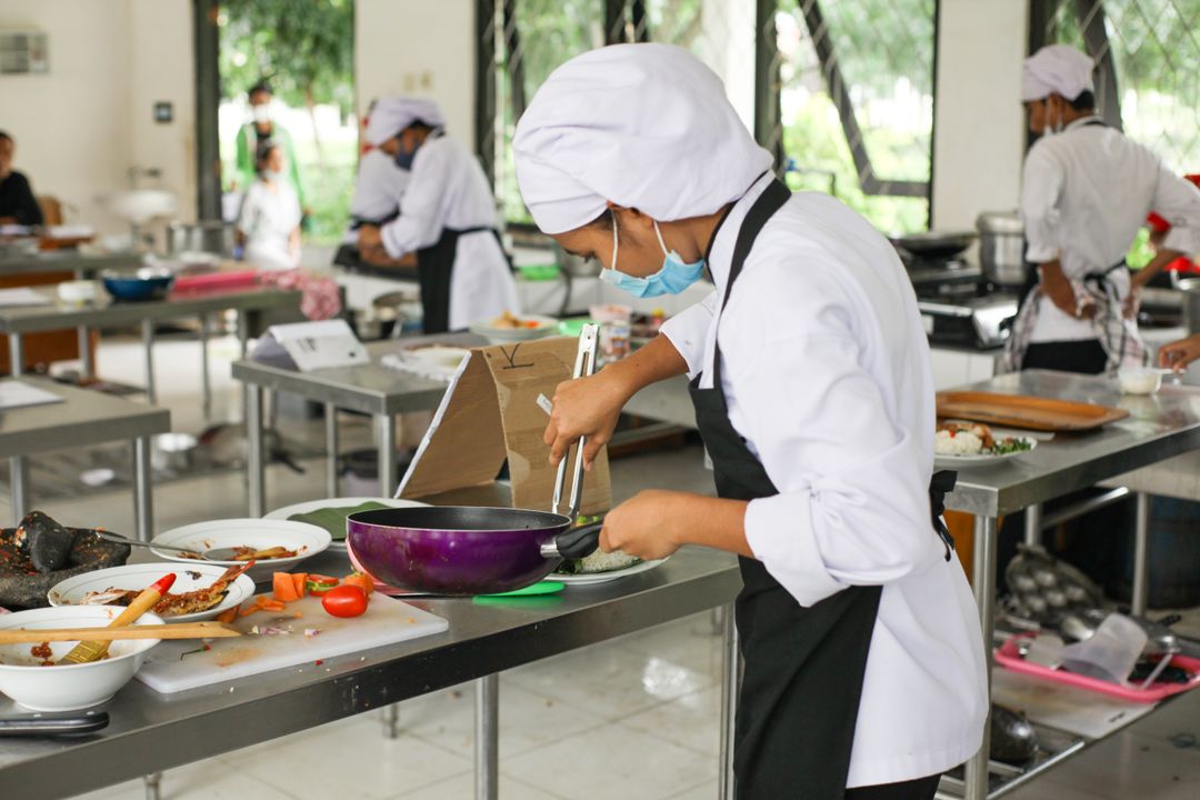 Pastry Chef Career Path in India: Salary, Stages, and How to Start (2026) 5 A culinary student in a white chef uniform practises food preparation techniques in a professional kitchen.