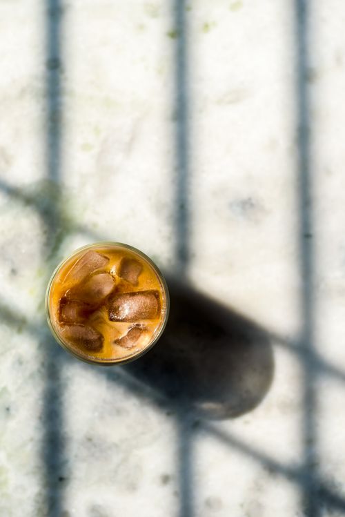 Free Top view of a glass of iced coffee on a marble surface with shadows. Stock Photo