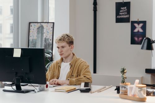 Free Young man concentrating on a computer screen at his modern workspace. Stock Photo