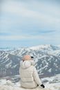 Person in White Winter Coat and Brown Knit Cap Standing on Snow Covered Mountain