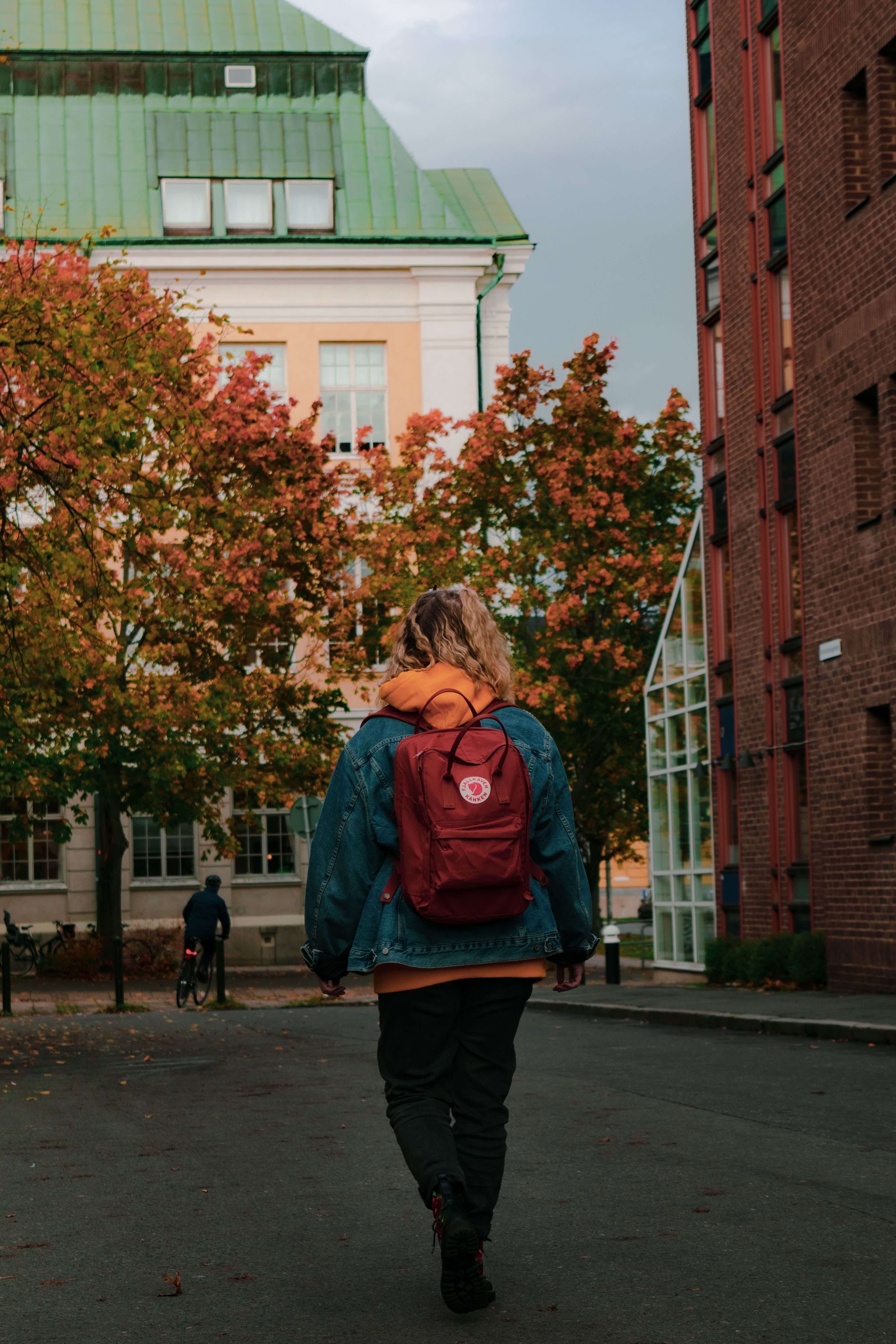 Back View of a Woman Walking with a Red Backpack · Free Stock Photo