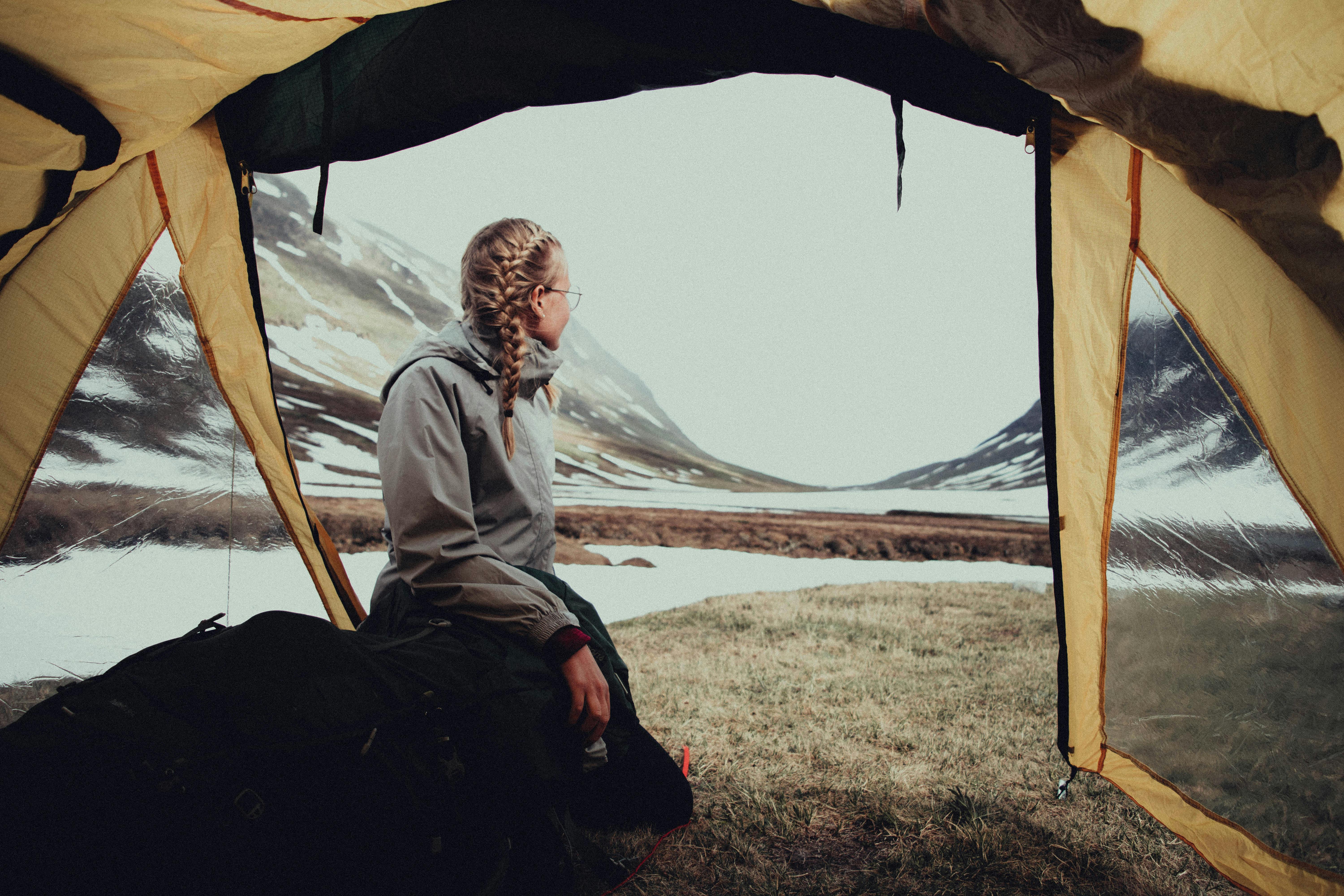 a woman in gray jacket sitting beside the tent