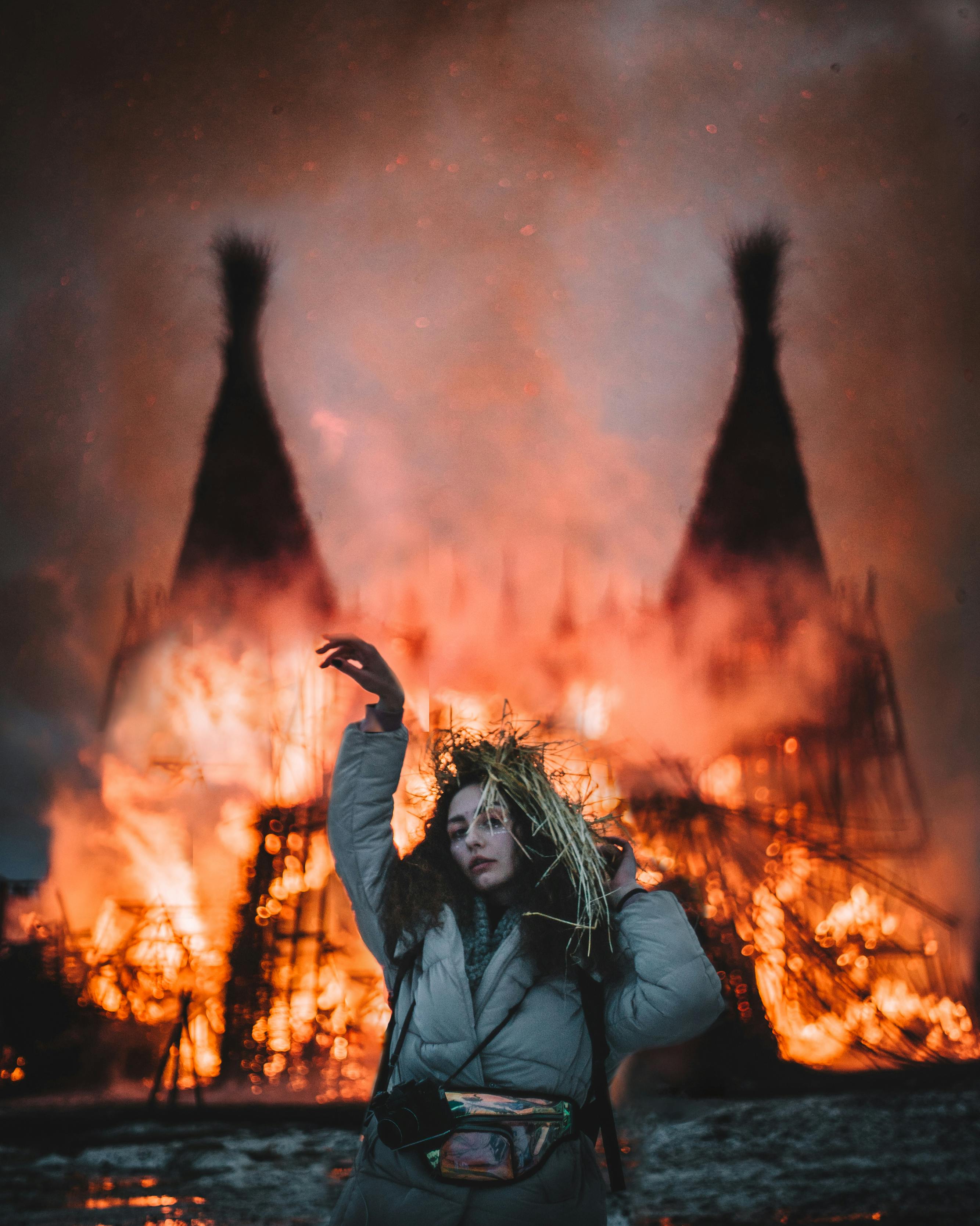 Creative portrait of a woman posing dramatically in front of a fiery structure.