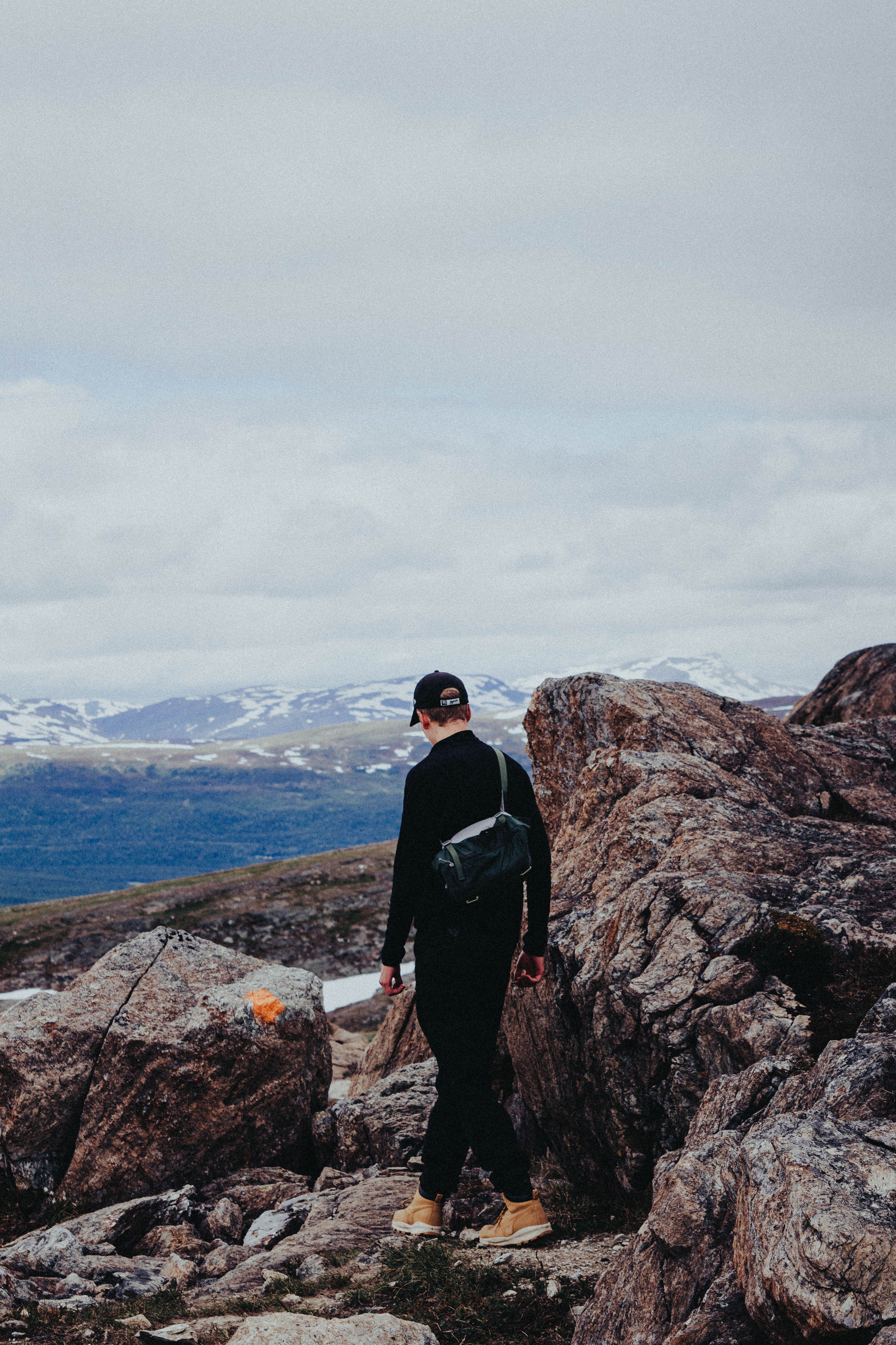 A Man in Black Jacket Standing on Rock Formation · Free Stock Photo