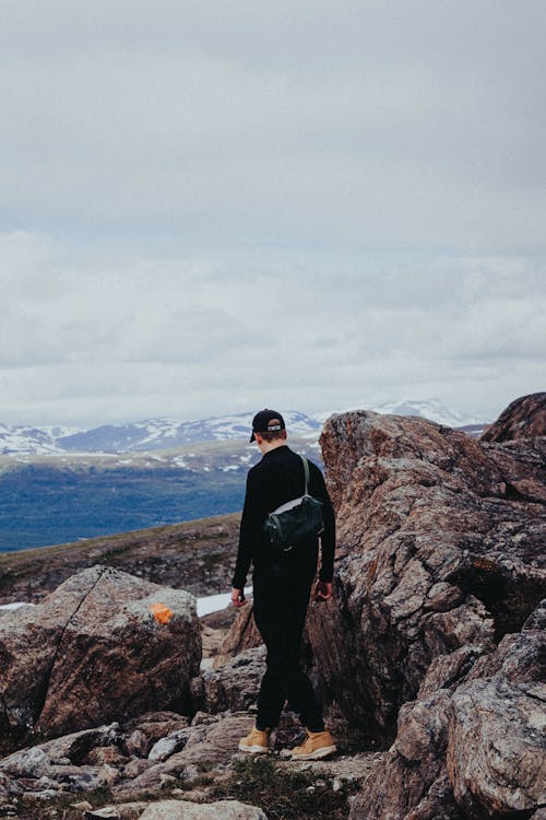 A Man in Black Jacket Standing on Rock Formation