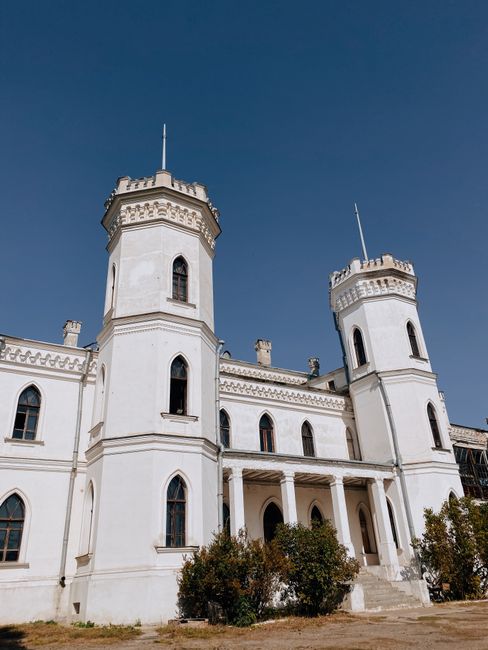 A stunning white castle with towers stands majestic under a clear blue sky.