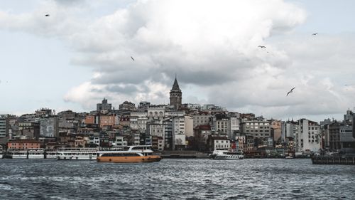 Free Scenic view of historic Galata Tower and Istanbul skyline across the Bosphorus with boats and cloudy sky. Stock Photo