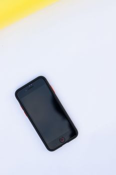 A modern smartphone placed on a minimalist white and yellow surface, perfect for technology-themed designs.