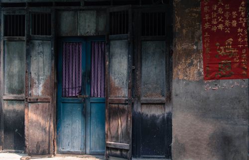 Free Rustic wooden doors with a traditional red Chinese poster, offering a vintage aesthetic. Stock Photo