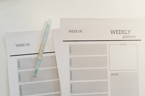 Free Organized weekly planner sheets with a pen for efficient scheduling and goal setting. Stock Photo