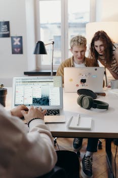 Young team collaborating at a modern workspace with laptops and headphones.