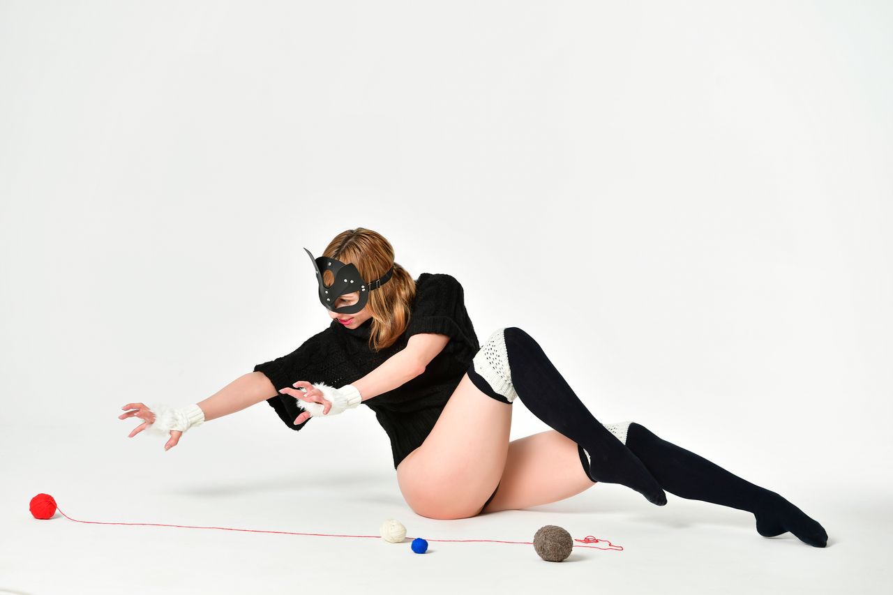 full body of female in catwoman costume sitting on floor with colorful