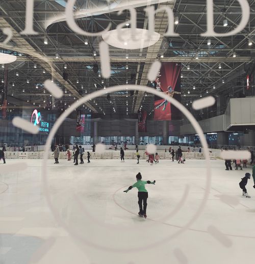 Free People ice skating at an indoor rink in Beijing with modern architectural design. Stock Photo
