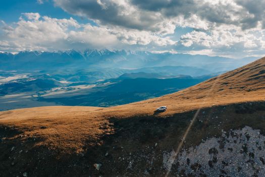 A drone shot of a car on a serene mountain landscape in Russia, showcasing stunning natural beauty.