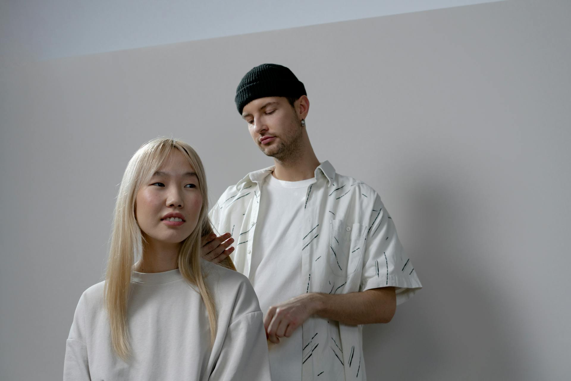 Photo of a Man in a White Shirt Styling a Woman's Hair