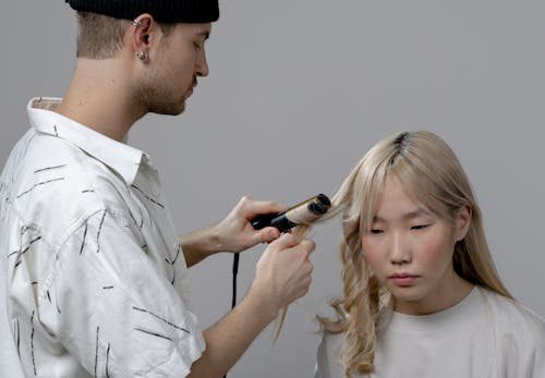 Free Photo of a Man Using a Curler on a Woman's Hair Stock Photo