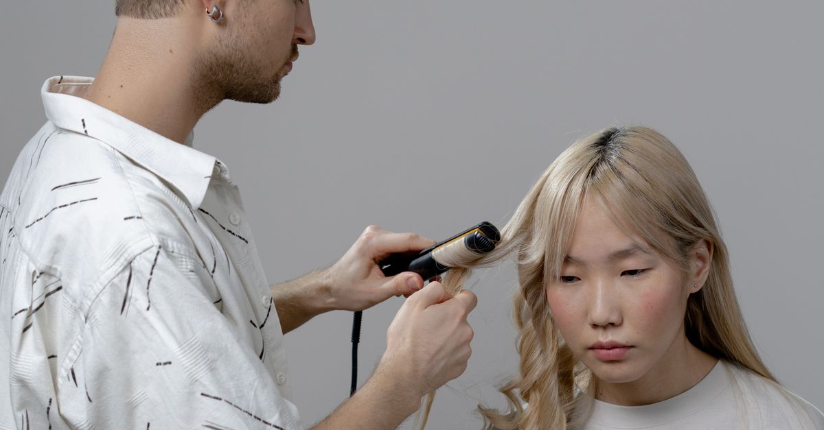 Photo of a Man Using a Curler on a Woman's Hair · Free Stock Photo