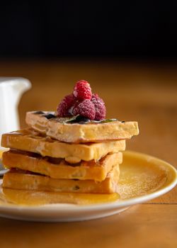 Delicious stack of waffles topped with fresh raspberries and syrup, perfect for a sweet breakfast treat.