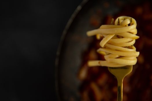 A golden fork with spaghetti and tomato sauce, perfect for Italian cuisine concepts.