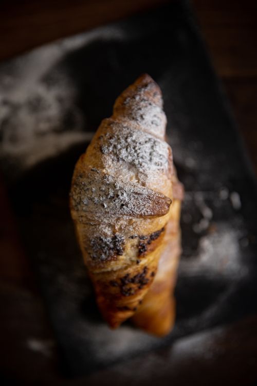 Free Close-up of a croissant dusted with powdered sugar on a slate board. Stock Photo