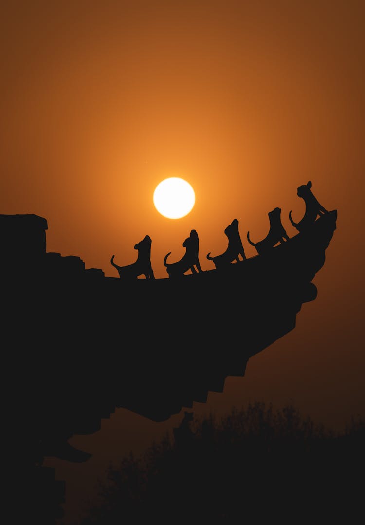 Silhouette Of Howling Dogs Statuettes On The Roof During Sunset