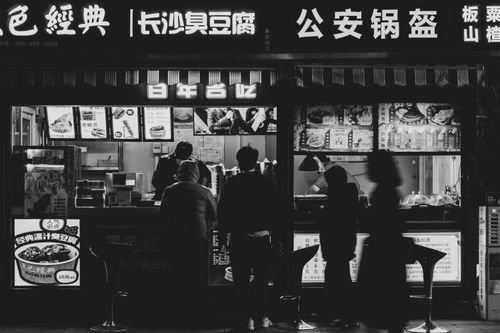 Free Silhouettes of people at a street food stall at night with vibrant signage. Stock Photo