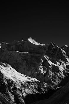 Stunning black-and-white photo of snow-covered mountains in Zermatt, capturing winter's dramatic beauty.