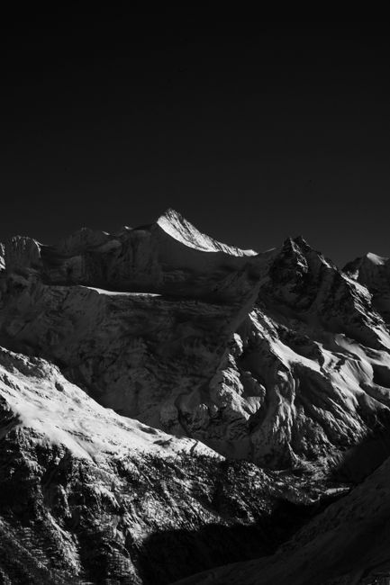 Stunning black-and-white photo of snow-covered mountains in Zermatt, capturing winter's dramatic beauty.