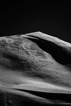 Dramatic black-and-white image of a snow-covered mountain peak, showcasing nature's rugged beauty.
