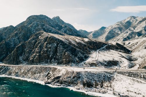 Free Scenic winter view of snow-covered mountains and winding road in Ongudaysky District, Altai, Russia. Stock Photo