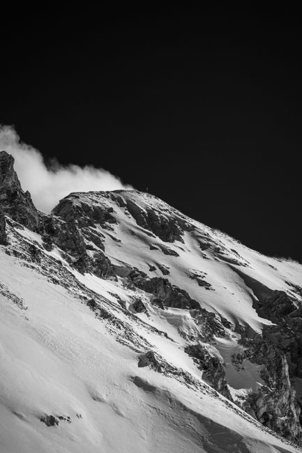Striking black-and-white photo of snow-covered mountain in winter, capturing nature's rugged beauty.