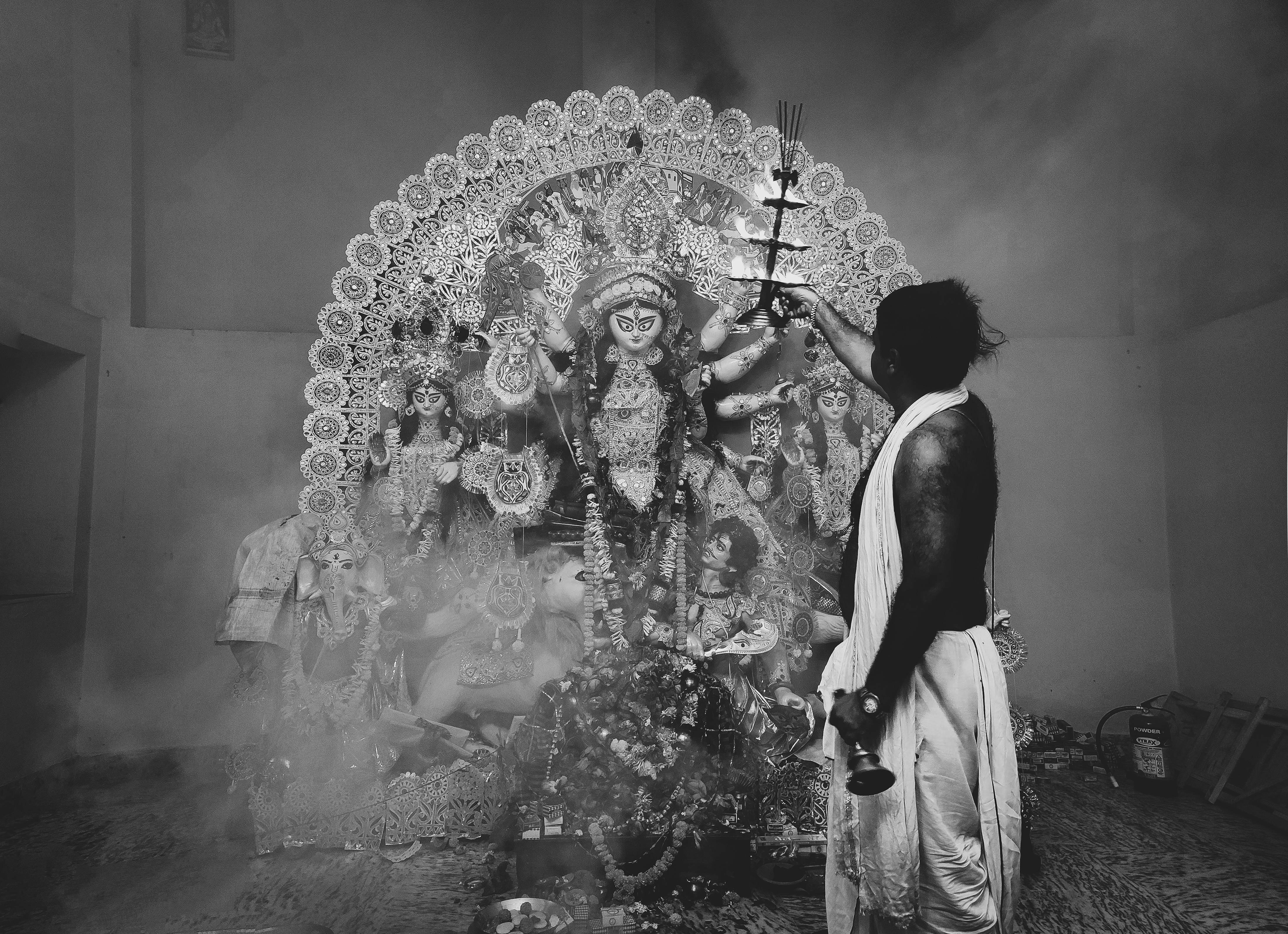 Monochromatic image depicting a traditional Hindu ritual with a goddess statue.