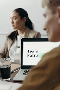 Professional team reviewing project during a retro meeting with laptop focus.