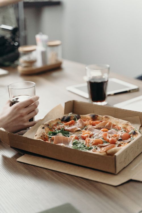 Free Delicious pizza and drinks on a table, perfect for a quick office lunch break. Stock Photo
