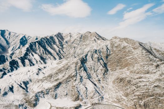 Breathtaking aerial photo of snow-covered mountains in Russia under a clear blue sky.