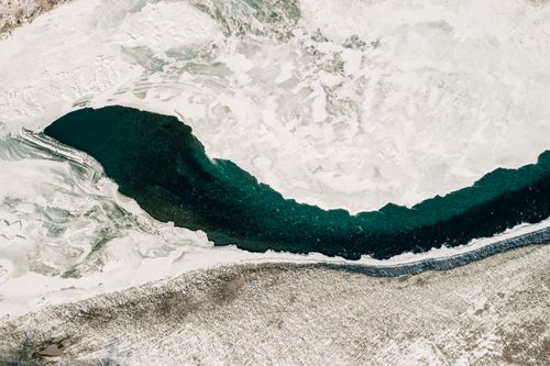 Free Stunning aerial shot of a frozen river winding through snow-covered landscape in Altay, Russia. Stock Photo