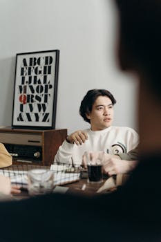 A focused young man sits in a modern office, engaging in discussion.