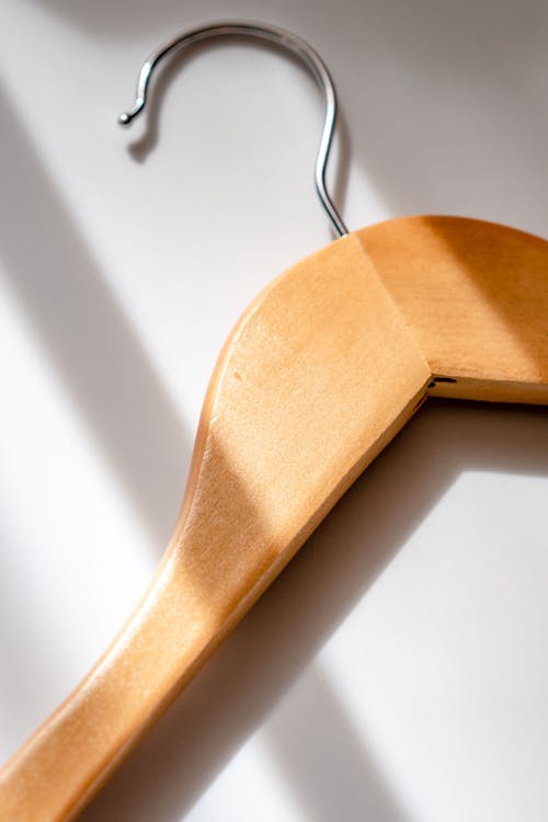 Free From above of wooden hanger for clothes placed on white surface in sunshine Stock Photo