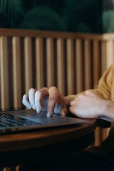 Person's hands typing on a laptop in a cozy indoor setting with a wooden background.
