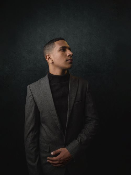 Free Portrait of a young man in a stylish gray suit against a dark background. Stock Photo