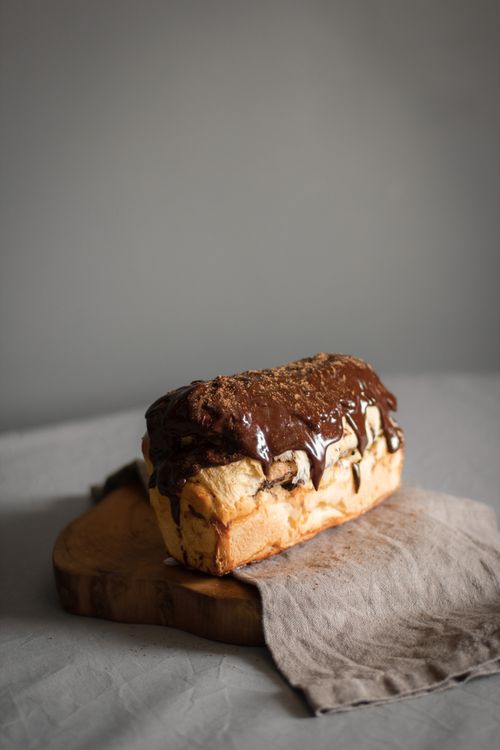 Free Tasty chocolate-covered loaf cake resting on a rustic wooden board, perfect for desserts. Stock Photo