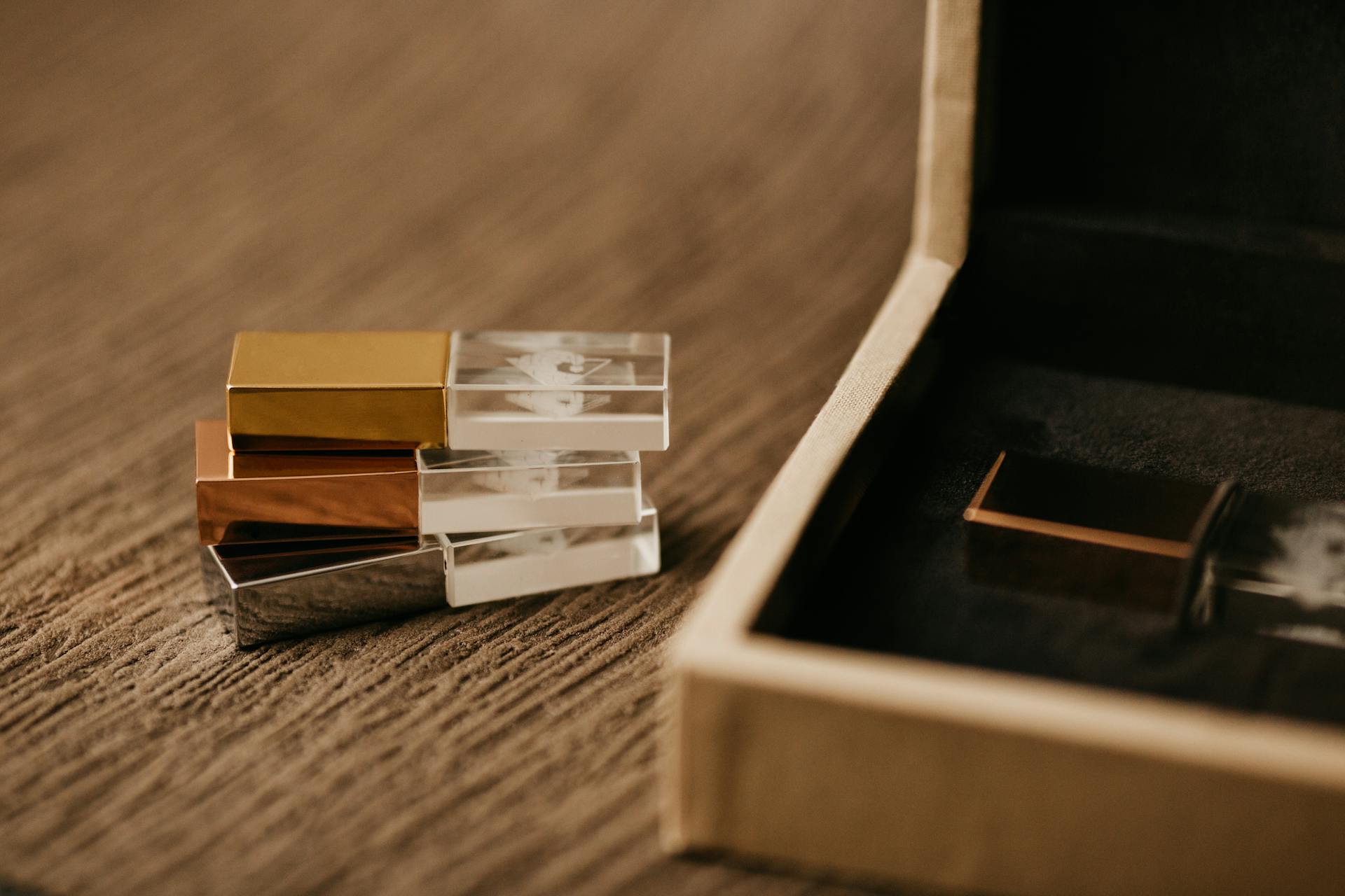 Heap of modern USB flash drives against wooden box on rough surface on blurred background