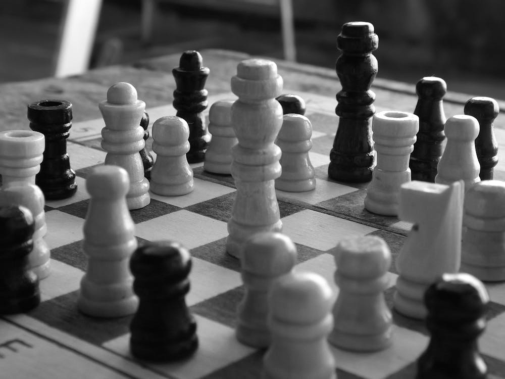 Grayscale Photograph of Chess Pieces on a Chessboard