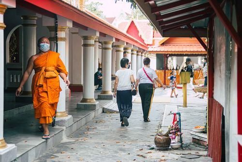 Free A serene temple scene with a Buddhist monk and visitors exploring the courtyard. Stock Photo