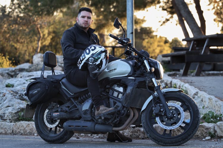 Man Holding A Helmet Sitting On A Motorcycle