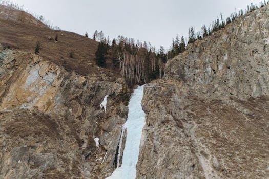 A scenic frozen waterfall amidst rocky terrain in Ongudaysky District, Altai, Russia.