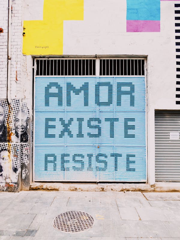 Exterior of shabby wall of urban building with phrase in Portuguese Amor Existe Resiste on street of modern city