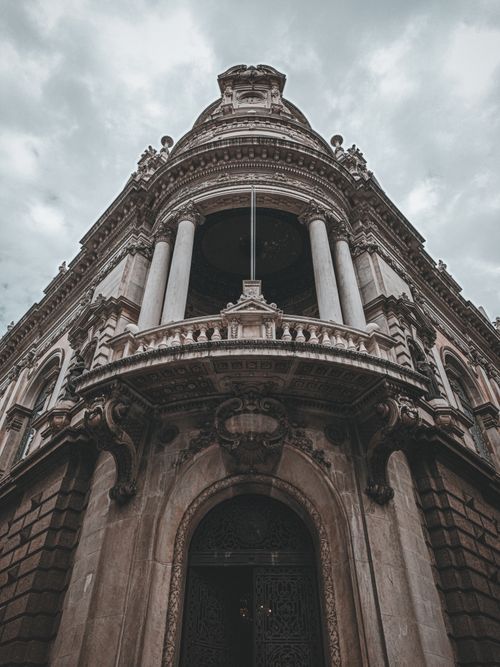 Free From below of aged masonry house exterior with columns and decorative friezes under cloudy sky in city Stock Photo